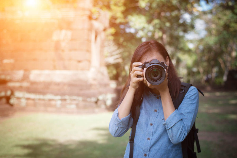 Young attractive woman photographer tourist with backpack coming to shoot photo at ancient temple in Naples